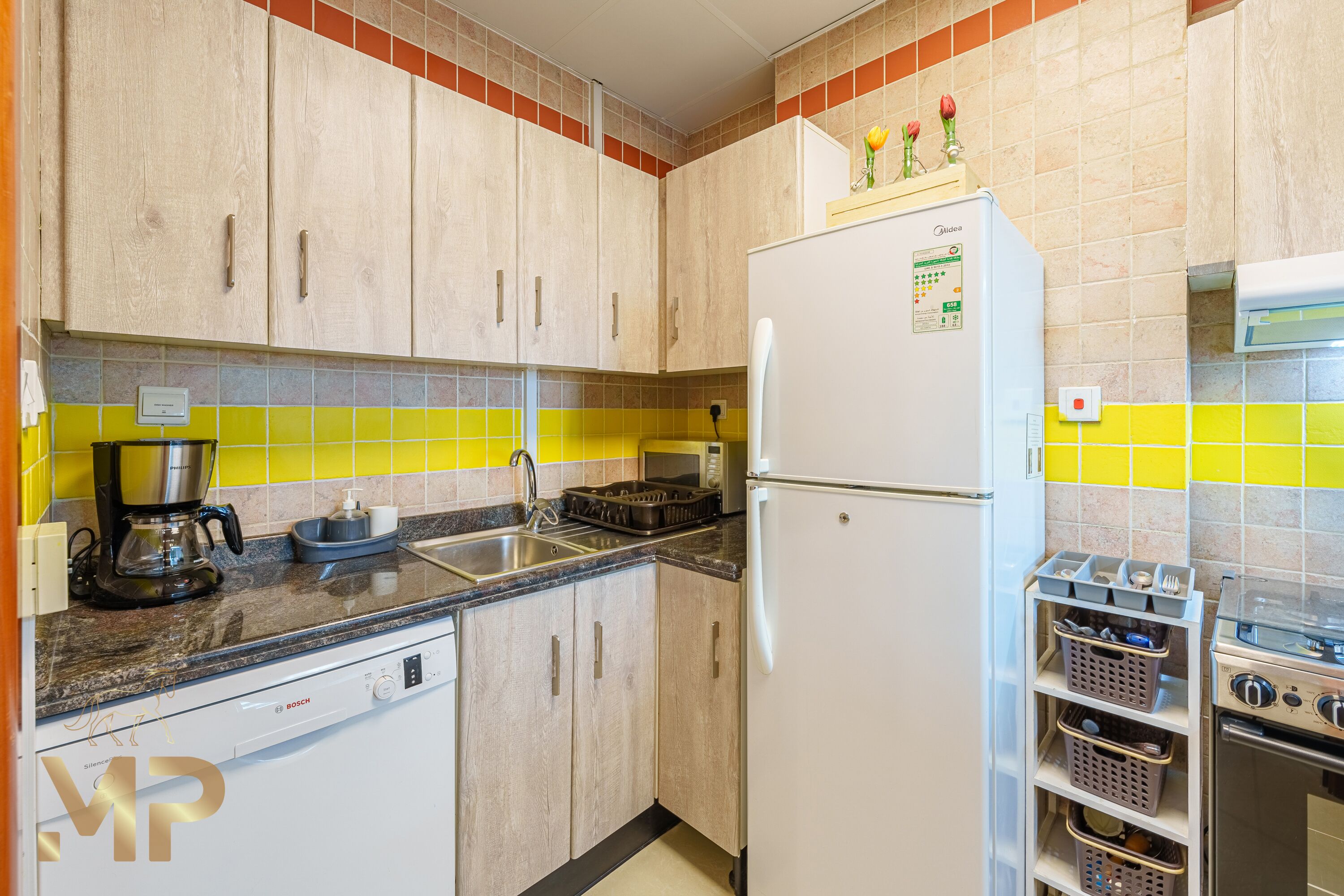 Een keuken met houten kastjes, een witte koelkast, een Bosch vaatwasser, een magnetron en een gasfornuis.