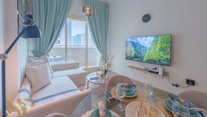 Una camera d'hotel moderna con un'ampia finestra, una TV a schermo piatto, un'area pranzo e un divano.
