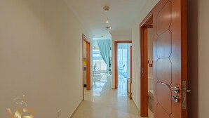 Un corridoio con pavimento piastrellato, una porta in legno con motivo geometrico e un soffitto con faretti.