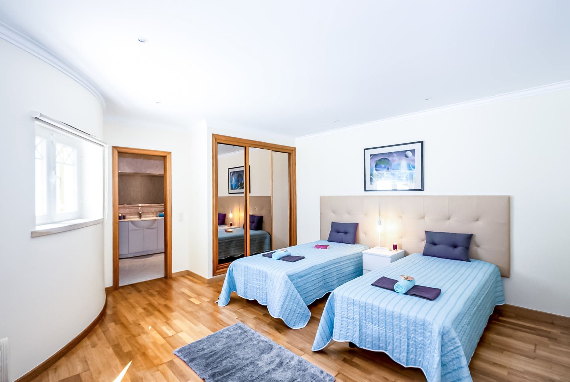 Un dormitorio con dos camas, un armario, un baño y una ventana.