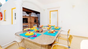 A dining area with a brick oven, a table set for breakfast, and a view of the sky.