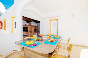 A dining area with a brick oven, a table set for breakfast, and a view of the sky.