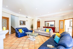 A spacious living room with a blue sofa, a grey sofa, and a coffee table.