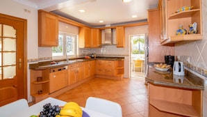 A kitchen with wooden cabinets, a built-in oven, a coffee maker, and a fruit bowl.