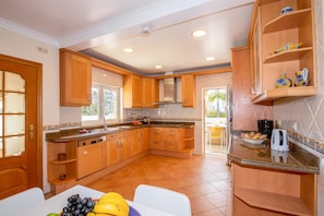 A kitchen with wooden cabinets, a built-in oven, a coffee maker, and a fruit bowl.