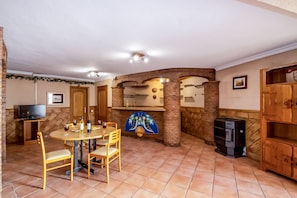 A dining area with a round table, chairs, a television, and a fireplace.