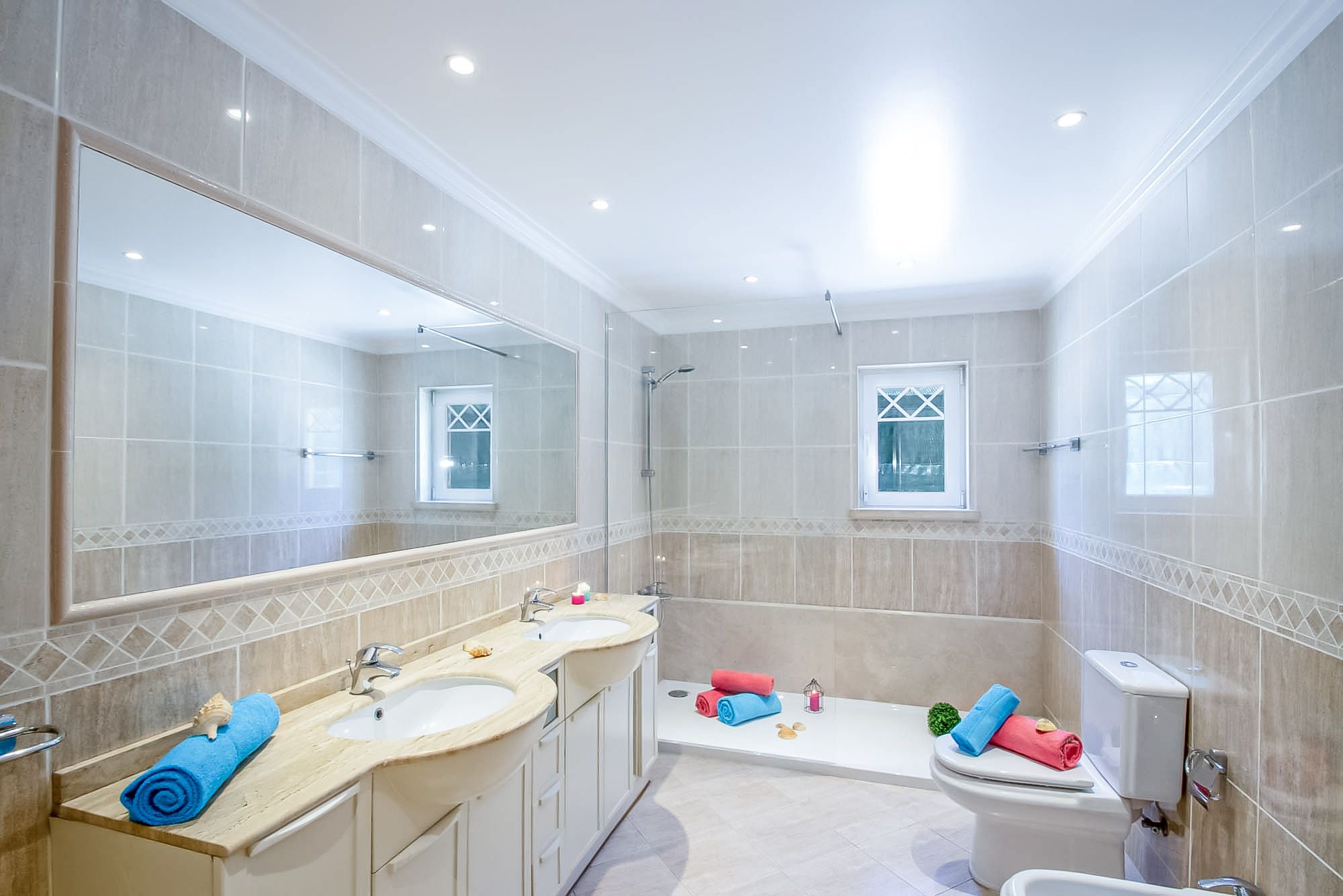 A modern bathroom with two sinks, a bathtub, and a toilet.