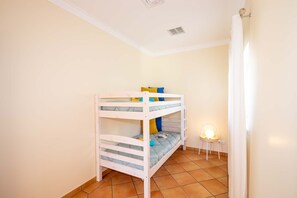 A bunk bed in a room with a tiled floor and a small chair with a light.