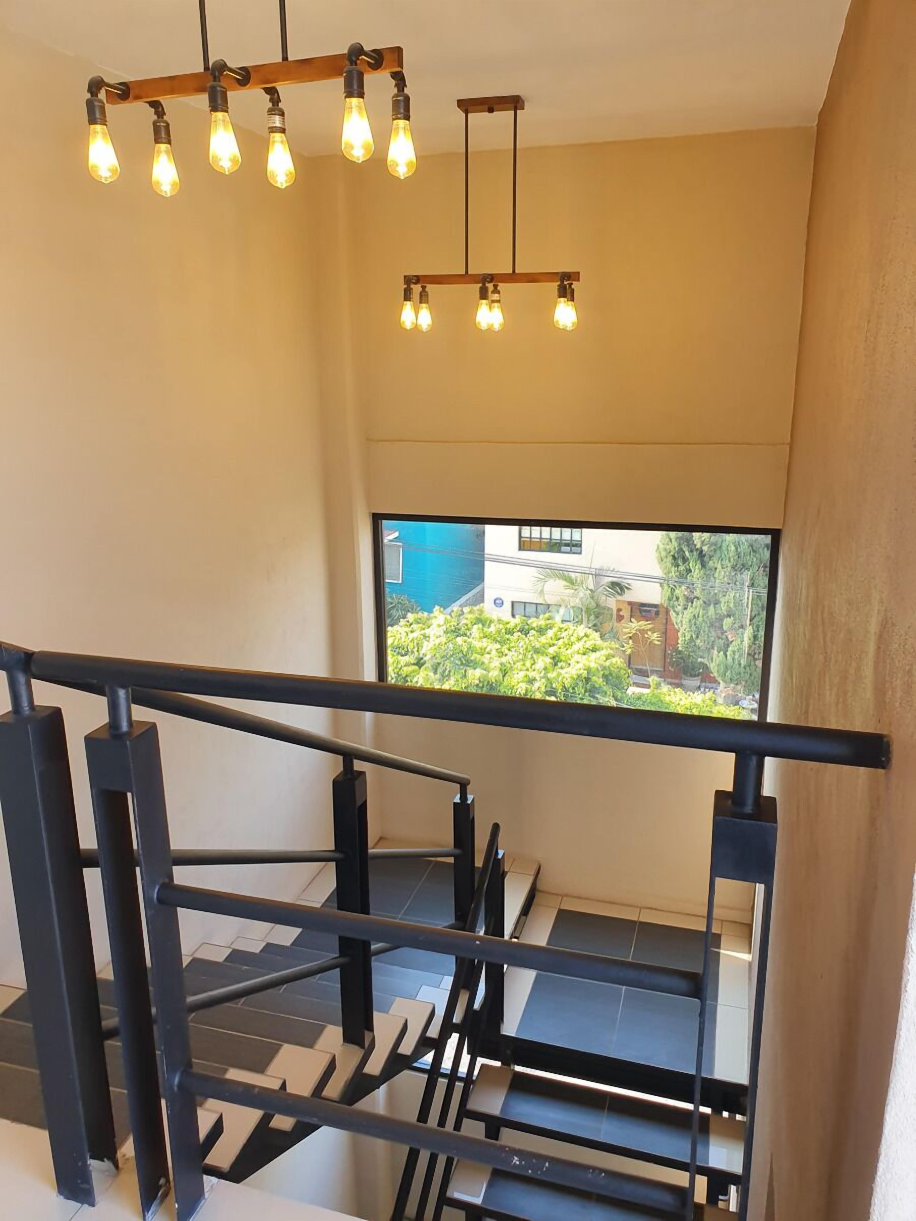 A modern staircase with black railings and a view of greenery outside.