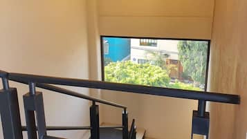 A modern staircase with black railings and a view of greenery outside.