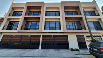 A multi-story building with a flat facade, large windows, and a row of garage doors labeled G1, G2, and G3.