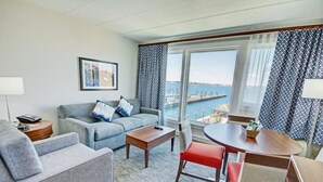 A hotel room with a sofa, a small table, a dining table with chairs, and a view of the sea. - A PLUS room at Wyndham Inn on the Harbor, perfect location (Newport)