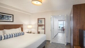 A hotel room with a large bed, a bedside lamp, a mirror, and a TV. - A PLUS room at Wyndham Inn on the Harbor, perfect location (Newport)