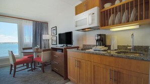 A compact kitchen with wooden cabinets, a microwave, a coffee maker, and a dining area with a TV. - A PLUS room at Wyndham Inn on the Harbor, perfect location (Newport)