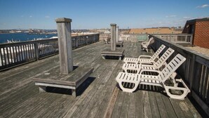 A wooden deck with lounge chairs and a bench overlooking a body of water. - A PLUS room at Wyndham Inn on the Harbor, perfect location (Newport)