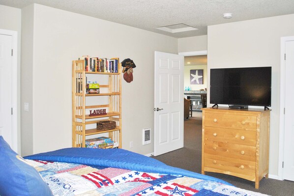 A bedroom with a bed, a bookshelf, a dresser, and a television.
