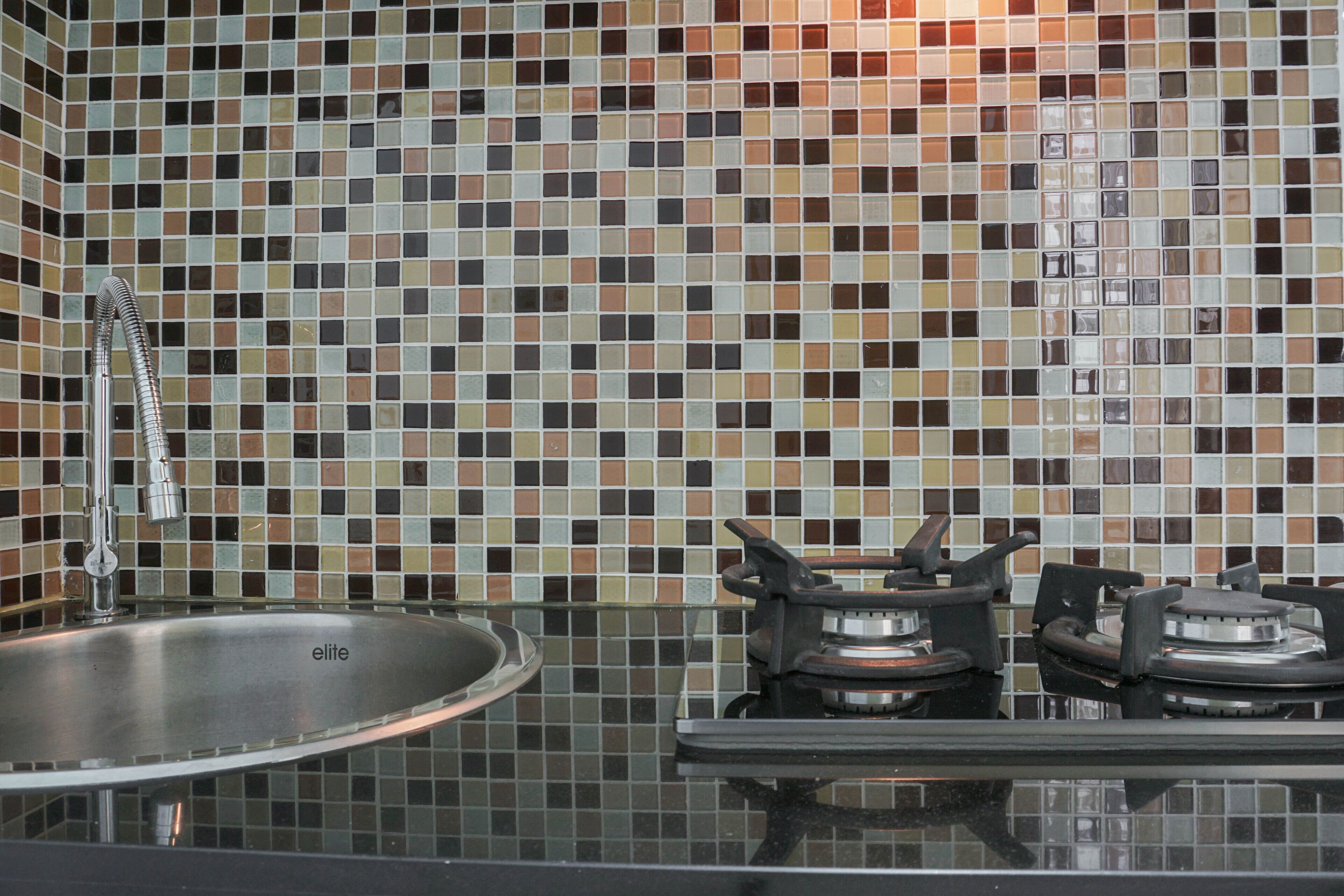 A kitchen with a tiled backsplash, a stainless steel sink, and a gas stove.