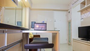 A modern kitchen with a bar area, a television, and a minibar.