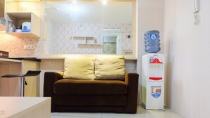 A compact living space with a sofa, a water dispenser, and a kitchenette area.