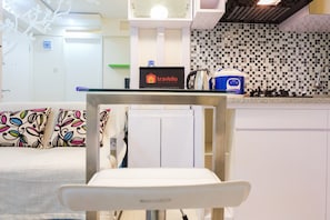 A modern kitchen with a white countertop, a travelio sign, and a kettle.