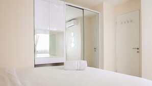 Une chambre d’hôtel comprenant un lit, un grand miroir, une armoire et une porte avec des crochets.