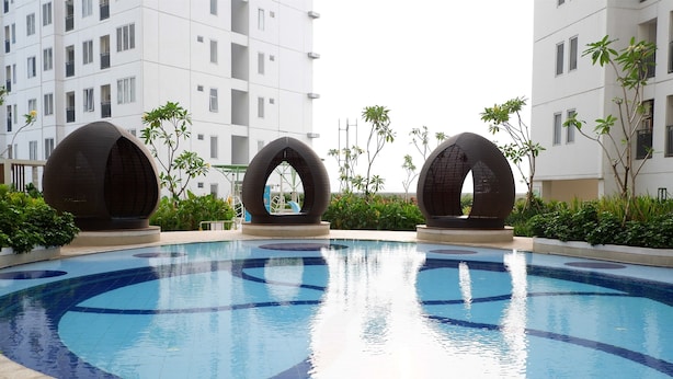 Une piscine avec trois grandes structures sphériques au centre, entourée de verdure et de bâtiments modernes en arrière-plan.