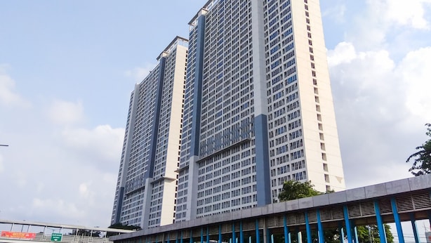 Um edifício alto com design arquitetônico moderno, apresentando uma grade de janelas e um colunar central imponente.