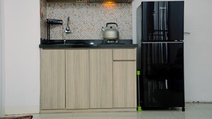 A kitchen with wooden cabinets, a black refrigerator, a gas stove, and a tiled backsplash.