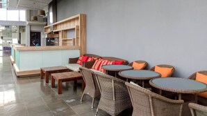 A modern cafe with wicker furniture, a wooden counter, and a seating area with a bench and tables.