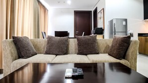 A modern living room with a sofa, a coffee table, a television, and a refrigerator.