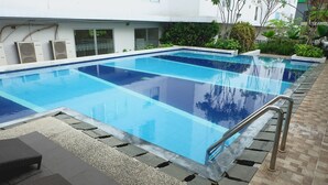 Une piscine rectangulaire à l’eau d’un bleu limpide, entourée d’une terrasse carrelée et agrémentée de quelques chaises longues.