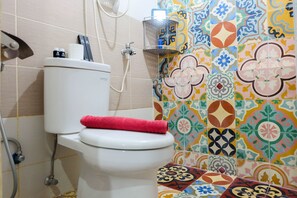 A bathroom with a toilet, a shower, and colorful tiles on the walls. - Compact and Comfy 2BR Bassura City Apartment (Jakarta)