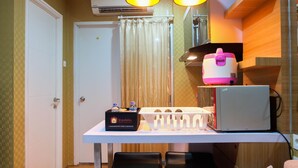 Une chambre d’hôtel compacte, dotée d’un bureau blanc, d’une boîte pour les voyageurs, d’un four à micro-ondes et d’un petit réfrigérateur.