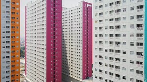 A high-rise residential building with multiple balconies and a uniform facade. - Best Furnished 2BR Mall Access at Green Pramuka Apartment (Jakarta)