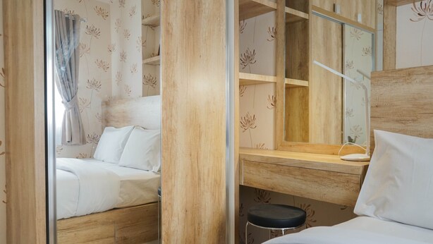 A compact hotel room with a bed, a small desk, and a mirror. - Best Furnished 2BR Mall Access at Green Pramuka Apartment (Jakarta)