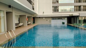 Ein moderner, überdachter Pool mit Holzterrasse, integriertem Sitzbereich und Blick auf die umliegende Bebauung.