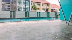 A swimming pool area with a modern building in the background. - Best Homey Elegant Studio Room at Amethyst Apartment (Jakarta)