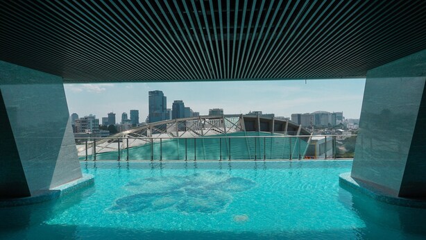 Una piscina interna con vista sulla città, che include un ponte e grattacieli.