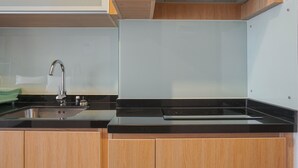 Una cucina moderna con lavello in acciaio inossidabile, piano di lavoro nero, mobili in legno e cappa aspirante integrata.