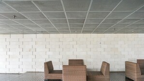 Zona salotto con parete in mattoni bianchi e soffitto a griglia metallica.