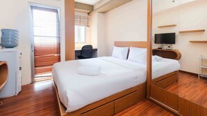 A neatly arranged bedroom with a bed, a TV, and a wardrobe. - Homey and Cozy Living Studio at Pakubuwono Terrace Apartment (Jakarta)