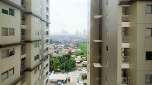 A high-rise building with multiple balconies and a view of a residential area with houses and cars below. - Homey and Cozy Living Studio at Pakubuwono Terrace Apartment (Jakarta)