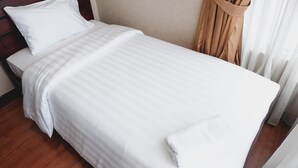 A neatly made bed with white linens, a wooden headboard, and a beige wall. - 2BR Prestige Dharmawangsa Essence Apartment Suites (Jakarta)