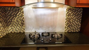 A kitchen with a black stovetop, three burners, and a stainless steel hood labeled 'MODENA'. - 2BR Prestige Dharmawangsa Essence Apartment Suites (Jakarta)
