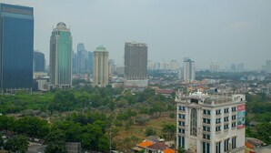 A cityscape with modern high-rise buildings, a mix of greenery, and a historic building with a dome. - Strategic 2BR at Sudirman Park Apartment (Jakarta)