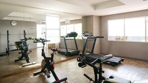 A gym with cardio machines, weight equipment, and large windows. - Wonderful 2BR Apartment at Belmont Residence Puri (Jakarta)