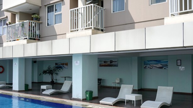 A hotel with a swimming pool, lounge chairs, and a balcony with potted plants. - Wonderful 2BR Apartment at Belmont Residence Puri (Jakarta)