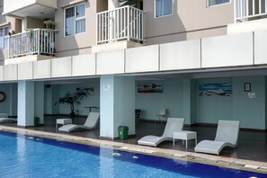 A hotel with a swimming pool, lounge chairs, and a balcony with potted plants. - Wonderful 2BR Apartment at Belmont Residence Puri (Jakarta)