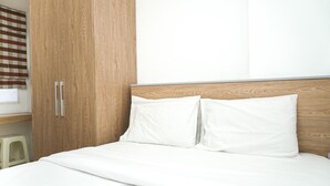 A neatly made bed with white bedding, a wooden headboard, and a wooden wardrobe with two doors. - Wonderful 2BR Apartment at Belmont Residence Puri (Jakarta)