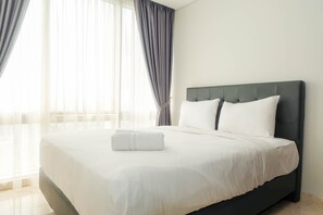 A neatly made bed with white linens and a folded towel, a dark headboard, and sheer curtains on a window. - Posh 2BR at The Empyreal Condominium Epicentrum Apartment (Jakarta)